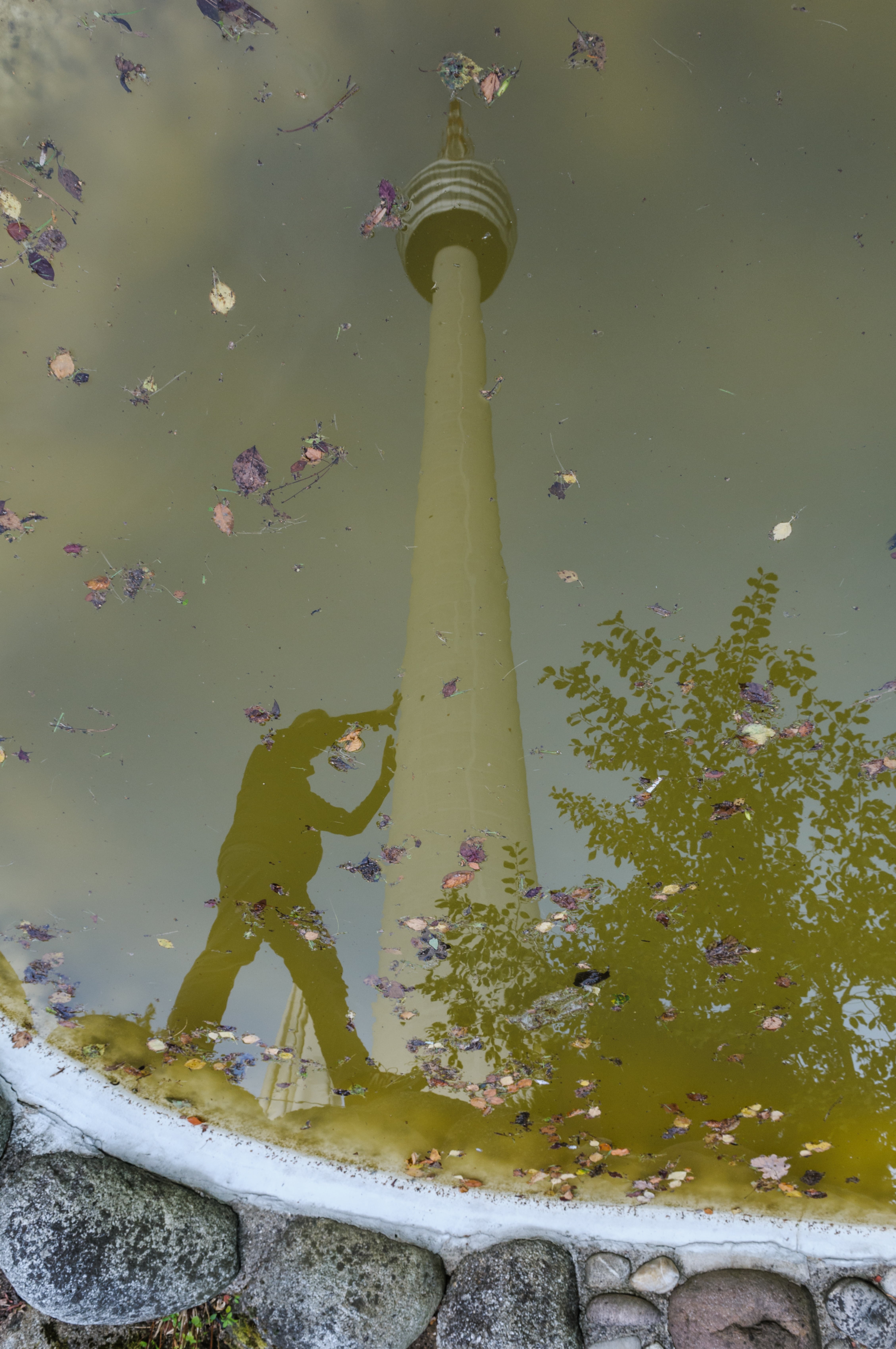 Fernsehturm in Wasser gespiegelt, gespiegelte Silhouette eines Menschen, der Fernsehturm zu stützen scheint