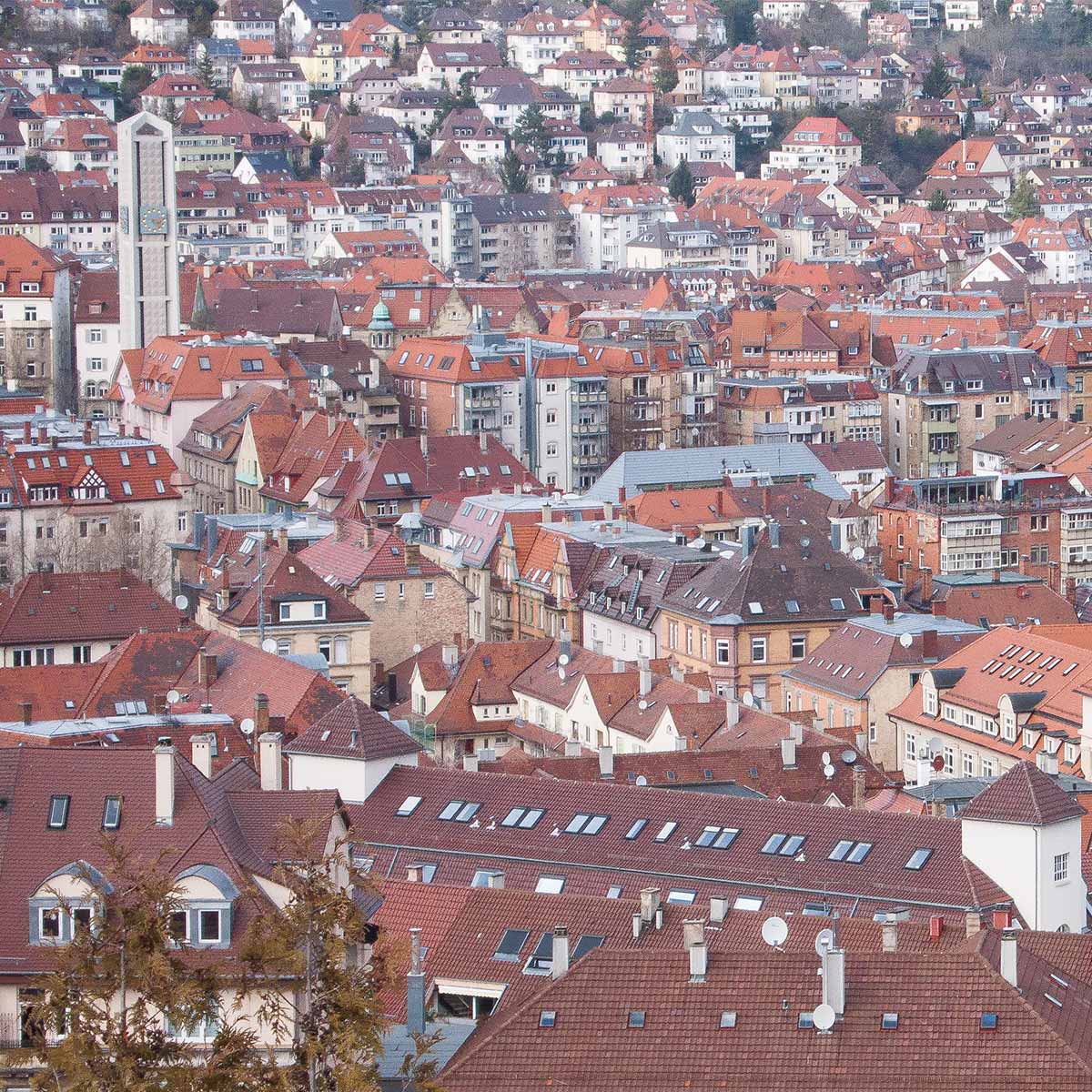 Blick von schräg oben über ein Häusermeer aus Altbauten, am Rand erhebt sich ein moderner Kirchturm über die Häuser